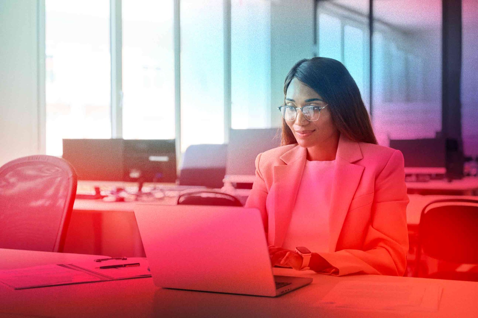smiling woman in blazer using business software on her laptop
