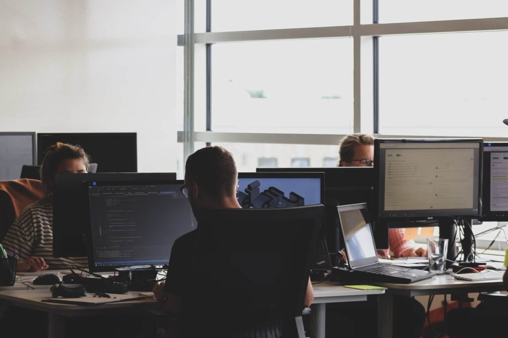 People in an office work on computers to solve customer problems efficiently and improve service for organizations